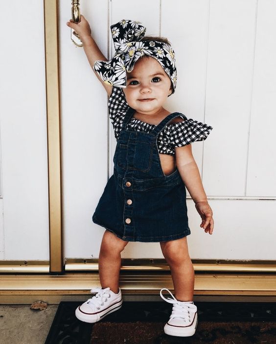 Petite fille coiffé d'un bandeau en tissu et portant une robe en jean